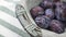 Fresh blue damson plums in lovely gray wicker basket on top of stripped cloth towel. Representation of Autumn Harvest.