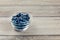 Fresh blueberries in small transparent glass bowl placed on wood