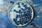 Fresh blueberries on the vintage ceramic plate over blue background.