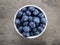 Fresh blueberries in white bowl on wood table