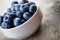 Fresh blueberries in white bowl on wood table