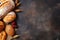 Fresh bread, buns, loaves, rolls, wheat ears on rustic black wooden background, text copy space, top view, flat lay