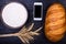 Fresh bread, flour, ears and a smartphone on a wooden table, top view.