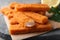 Fresh breaded fish fingers on grey board, closeup