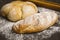 Fresh breads on dark wood with sprinkled flour.