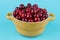 fresh bright cherries in a yellow bowl on a bright blue background