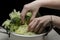 Fresh broccoli in women hands above the dish full of kale and cabbage .