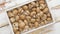 Fresh brown champignons in wooden crate, placed on white rustic table. Top view