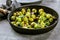 Fresh brussels sprouts in black iron pan on grey table