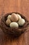 Fresh button quail eggs in a nest on wooden table background