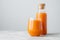 Fresh carrot juice in bottle with cork and glass,  over white background with copy space for your information. Healthy