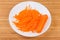 Fresh carrots chopped into thin long slices on white dish