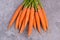 A fresh carrots on a grey structured background, close up