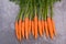 A fresh carrots on a grey structured background, close up