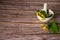 Fresh celandine with leaves and flowers in a porcelain mortar with a pestle on a wooden background.