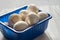 Fresh champignons in blue box on white wooden background. Close-up