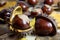 Fresh Chestnuts with Open Husk on an Old Rustic Wooden Table with Brown Autumn Leaves