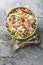 Fresh chickpea salami salad with iceberg and romaine lettuce, mozzarella, onion close-up in a bowl. Vertical top view