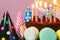 Fresh cholocate delicious cake with maracoons around it with topper Happy birthday and burning candles on the table