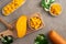 Fresh chopped, diced mango cubes on gray table background with tropical leaf