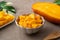 Fresh chopped, diced mango cubes on gray table background with tropical leaf