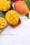 Fresh chopped mango on a tray and bright rustic wooden background. Tropical summer fruit design concept, close up, macro, copy