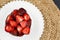 FRESH CHOPPED STRAWBERRIES SERVED ON WHITE PLATE AND JUTE TABLE