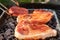 Fresh chops and a burger seen being placed on a disposable BBQ in an outdoor location.