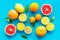 Fresh citrus background. Oranges, grapefruits, leaves - whole fruits and halfs - on blue background top-down