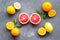 Fresh citrus background. Oranges, grapefruits, leaves - whole fruits and halfs - on grey background top-down