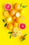 Fresh citrus background. Oranges, grapefruits, leaves - whole fruits and halfs - on yellow background top-down