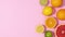 Fresh citrus fruits move on right side of pastel pink background with copy space. Stop motion flat lay