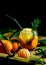 Fresh citrus juice in glass and ripe tangerines on wooden tray. Cold summer drink with citrus slices, ice and rosemary branch on