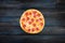 Fresh classic pepperoni pizzai on a dark wooden background. Top view center orientation