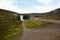 Fresh clean waterfall Gufufoss near Seydisfjordur in Iceland in summer with loads of water and curvy road, snow