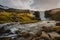 Fresh clean waterfall Gufufoss near Seydisfjordur in Iceland in summer with loads of water flowing between rocks, snow in the