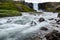 Fresh clean waterfall Gufufoss near Seydisfjordur in Iceland in summer with loads of water flowing between rocks, snow in the