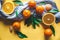 Fresh clementines, oranges on board with green leaves with a knife. Top view on a yellow background