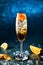 Fresh cocktail with champagne, orange and ice in wineglass on dark blue background. Summer cold drink and cocktail.