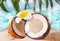 Fresh coconut on the sea sand. Plumeria frangipani for decoration. Sea or ocean, palm leaf on the background
