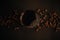 Fresh coffee in glass cup with coffee beans on black background flat lay. Drip or filter coffee. Dark moody image. Coffee brewing