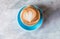 Fresh coffee with heart love foam in blue cup marble background