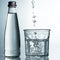 Fresh and cold, pure Water is poured into a glass with bottle. Purified water in a glass on a gray background. Motion freeze