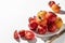 Fresh colorful tomatoes (red, yellow, orange) on white plate with hard shadows on textured background. Copy