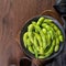 Fresh cooked boiled edamame in a plate on wooden tray and table background