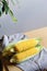 Fresh corn cobs with leaves on a wooden table over grey wall background. Raw corncobs on light brown wooden table, rustic style.