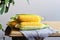 Fresh corn cobs with leaves on a wooden table over grey wall background. Raw corncobs on light brown wooden table, rustic style.