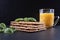 Fresh crackers, tomatoes and basil on a black stone on the table, next to orange juice