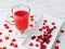 Fresh cranberry drink in a glass cup on a wooden white background