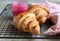 Fresh crispy croissants with pink honey on black metal grille, concrete background